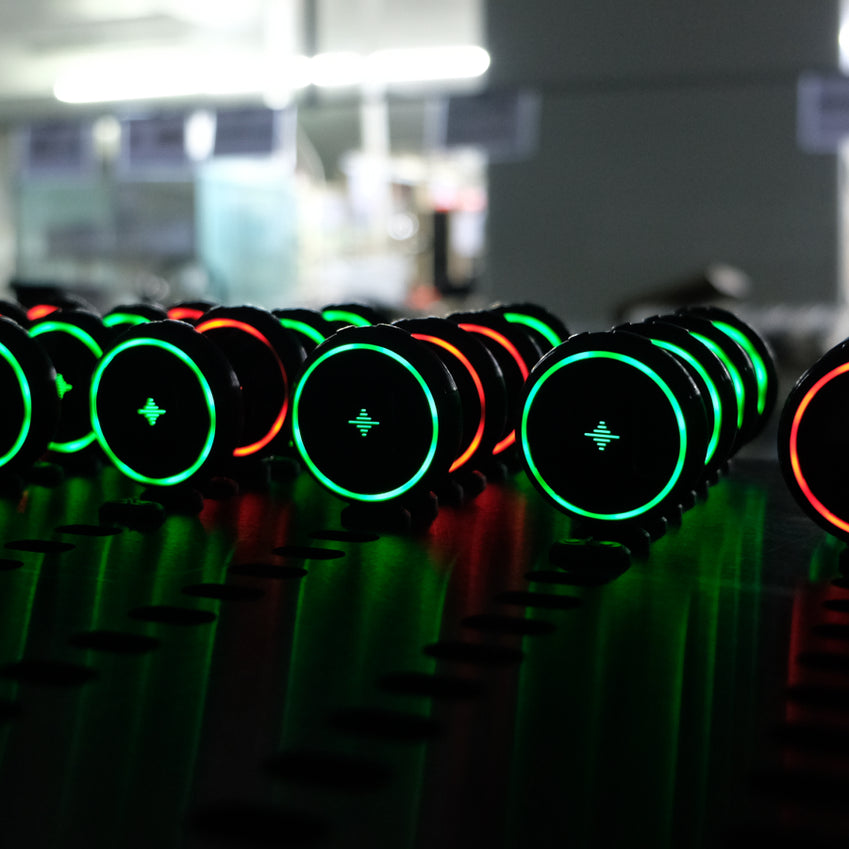File di metronomi elettronici rotondi neri con anelli luminosi verdi e arancioni