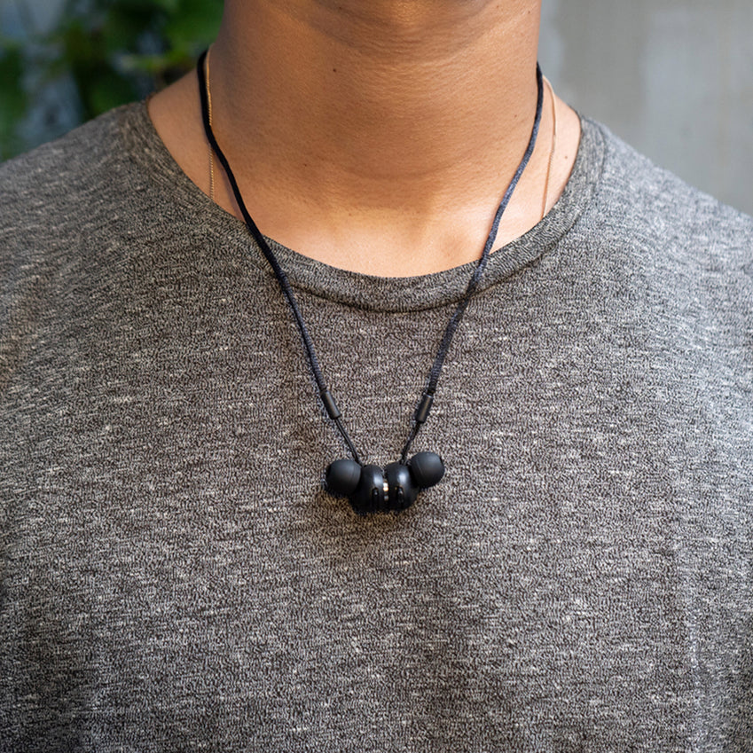 Black neck-worn earplugs resting against a person's gray shirt