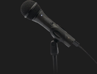 Black wired microphone mounted on a stand against a dark background