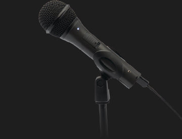 Black wired microphone mounted on a stand against a dark background