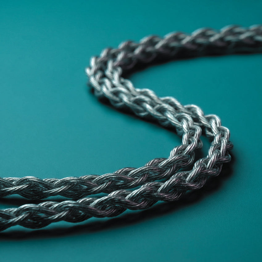 Close-up of a braided silver audio cable on a teal background