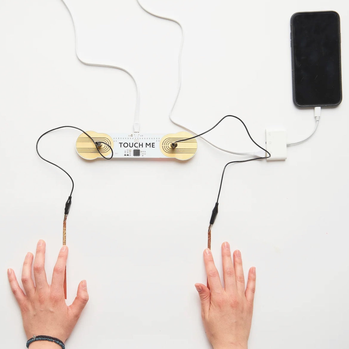Zwei Hände neben einem über Kabel und Kupferklebeband verbundenen Touch-Board