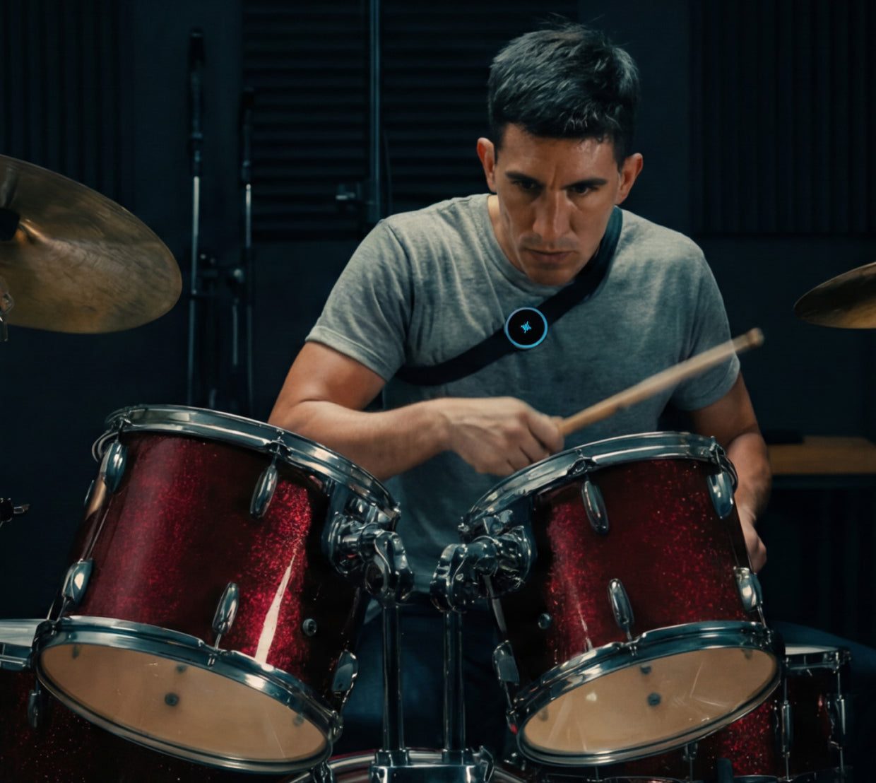 Drummer playing a red drum kit in a recording studio