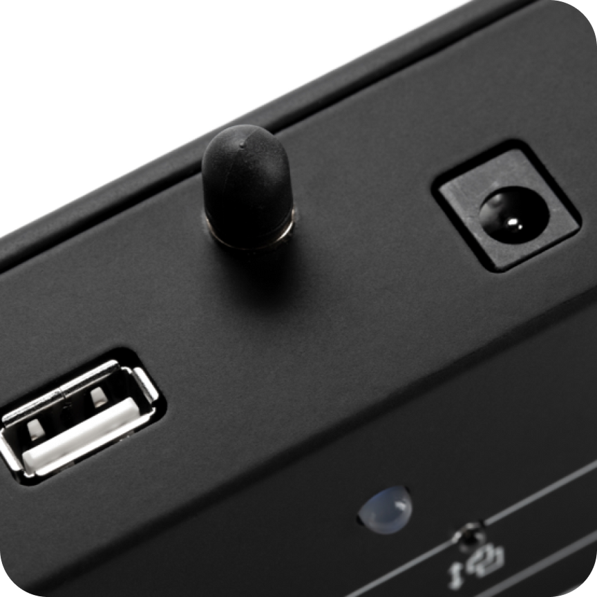 Close-up of a black electronic device with USB port and control knob on a white background