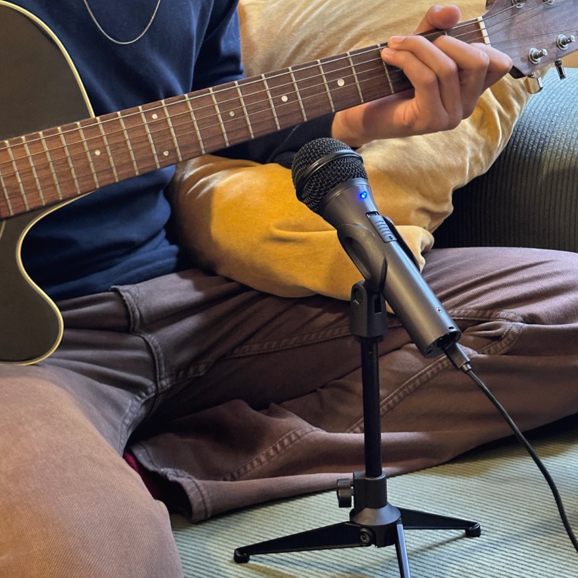 Flow microphone on a stand beside a person playing acoustic guitar