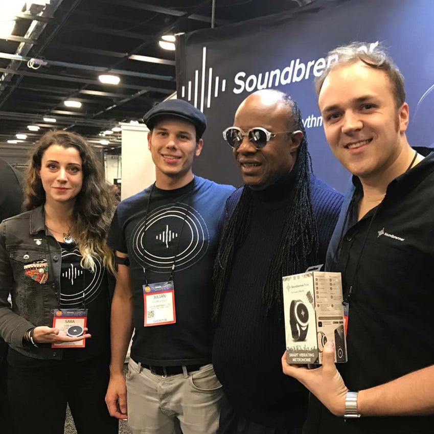 Four people standing at a Soundbrenner booth, with one holding a product package