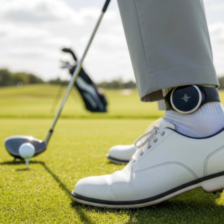 Pulse metronome worn on a golfer's ankle beside a golf club and ball