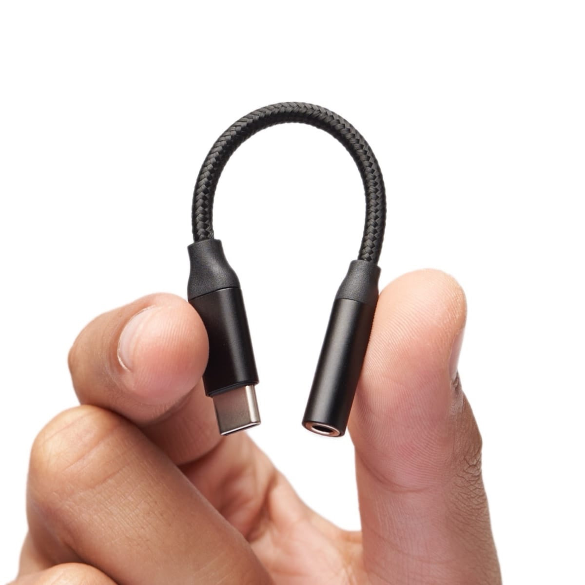 Una mano sosteniendo un adaptador de audio negro de USB-C a 3,5 mm
