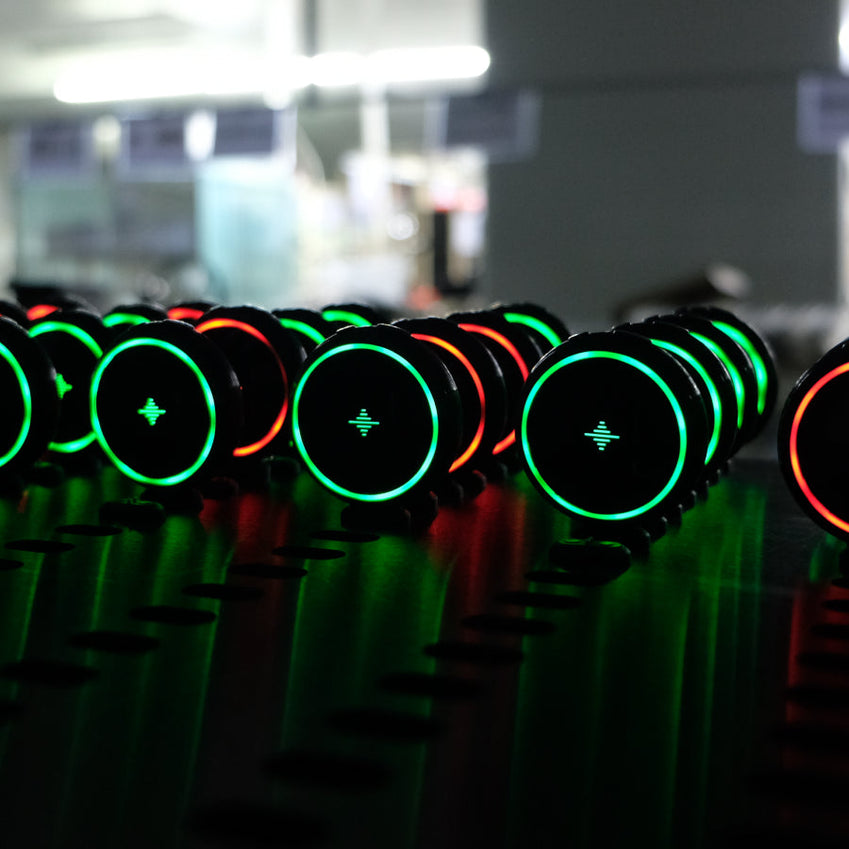 Rows of black round electronic metronomes with glowing green and orange rings