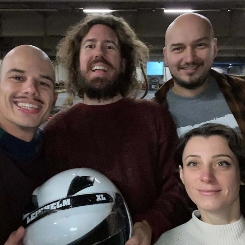 Four people posing indoors with a white helmet