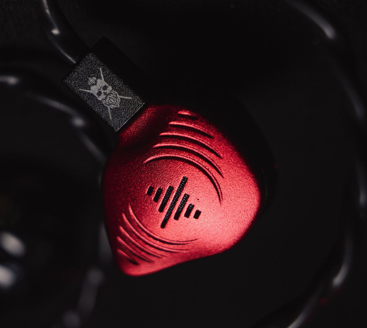 Close-up of the red Wave Pro 2 El Estepario Siberiano earpiece and skull detail on its cable connector