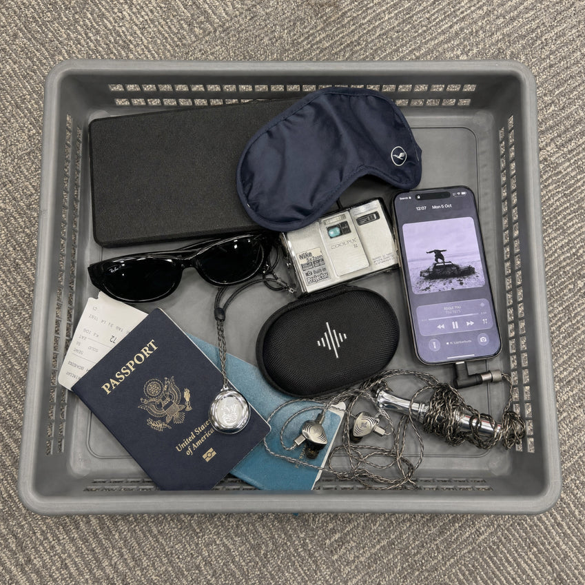 Wave Pro 2 carrying case and earphones with travel essentials in an airport security tray