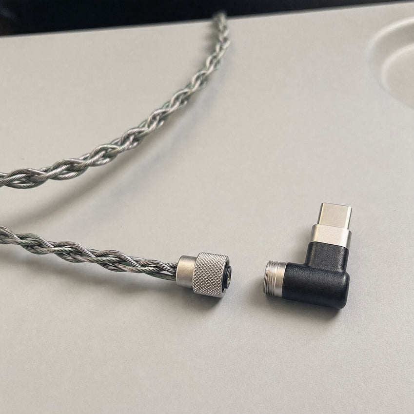 Wave Pro Hi-Fi USB-C connector beside the braided cable on an airplane tray table