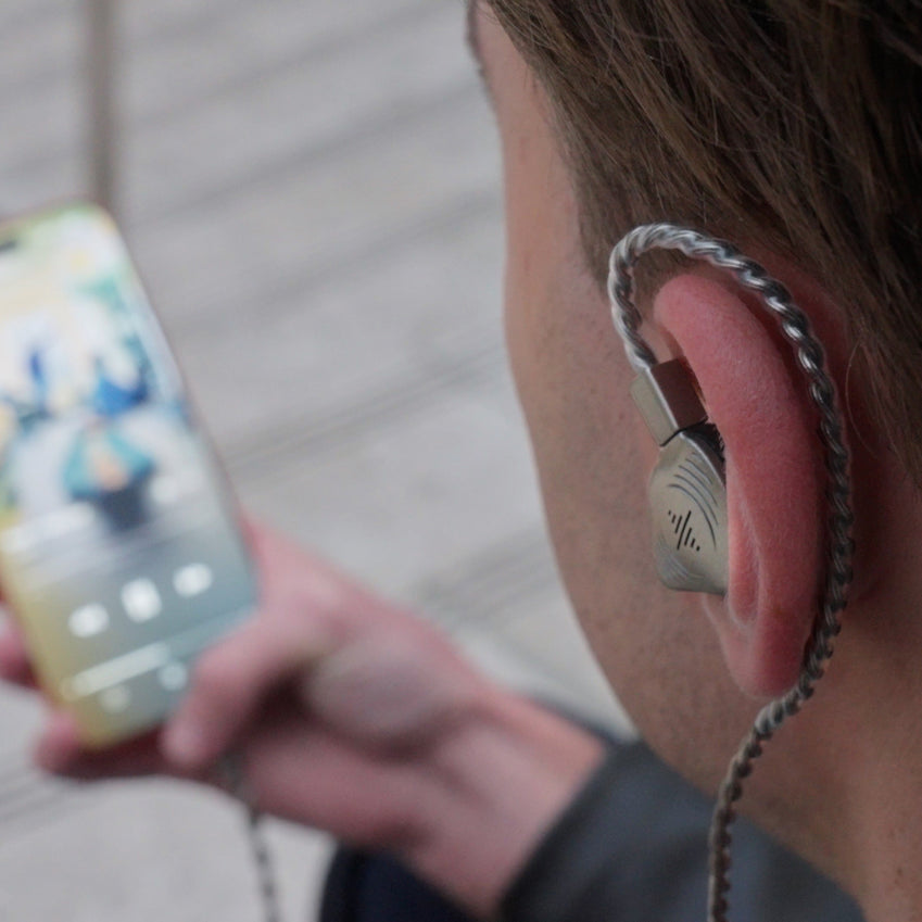 Person wearing Wave Pro in-ear monitors while listening to music on a phone