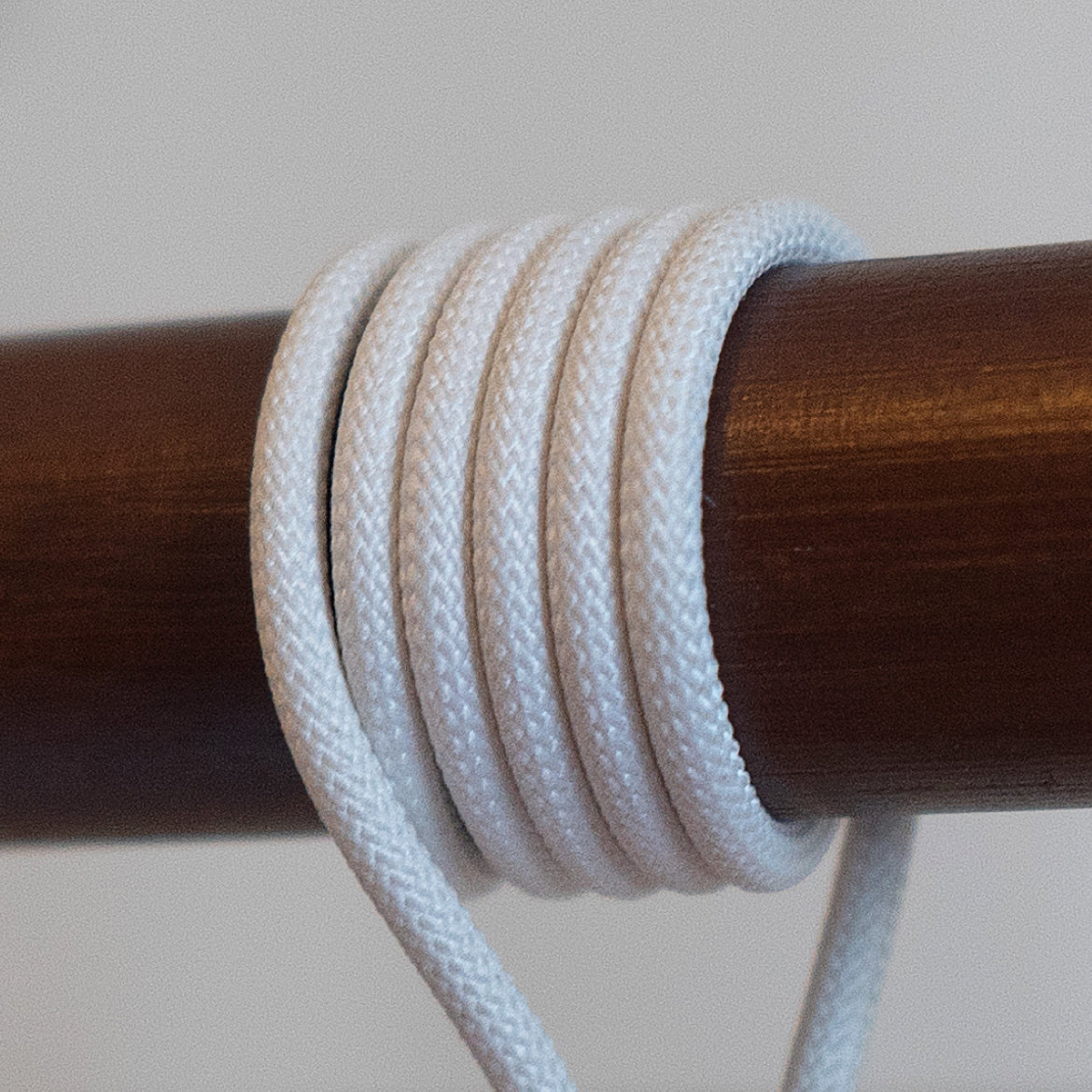 White braided cable coiled around a wooden rod