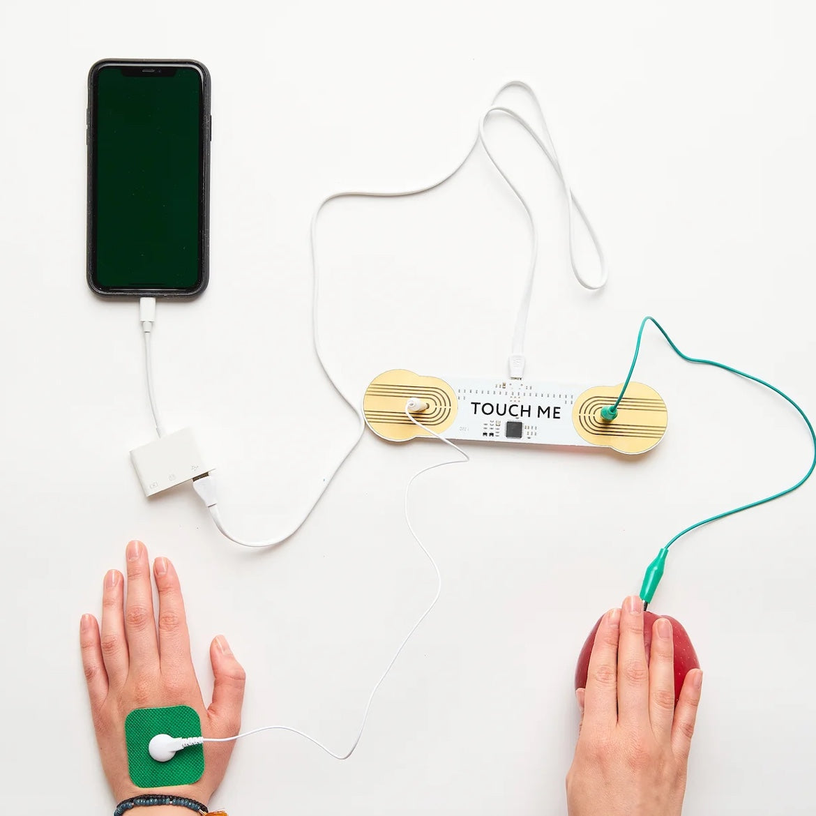 Mani con patch di collegamento accanto a un telefono e a una scheda elettronica Touch Me